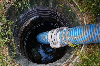 Assainissement en action d'une vidange de fosse. Photo d'un tuyau d'aspiration vidangeant une fosse septique.