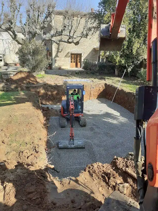 Photo de travaux d'assainissement montrant une mini pelle égalisant le sol